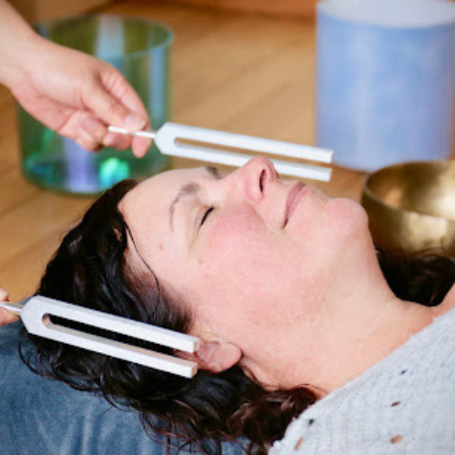 A lady laying down receiving tuning fork therapy