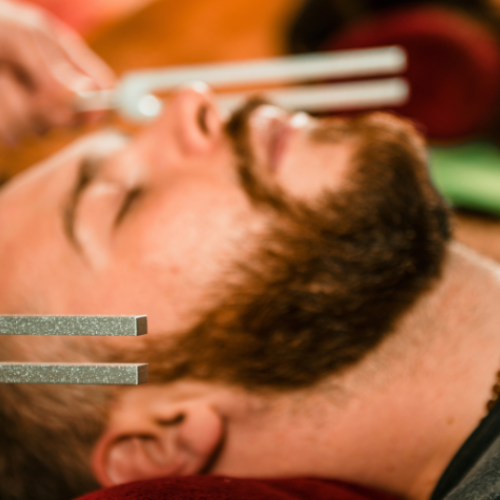 A man lying down getting tuning fork therapy